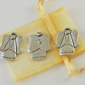 May include: Three silver angel charms with wings, one with a heart on its chest, in a yellow organza bag.