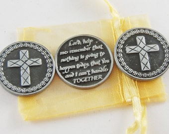Puede incluir: Tres fichas de metal plateadas con un diseño de cruz y una cita inspiradora: "Señor, ayúdame a recordar que nada va a pasar hoy que tú y yo no podamos manejar JUNTOS".
