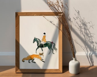 May include: Watercolor print in a wooden frame. The artwork depicts a rider on a dark horse, with a fox running below. The rider wears an orange jacket and black helmet. The fox is orange and white. A white vase with dried flowers is in the foreground.