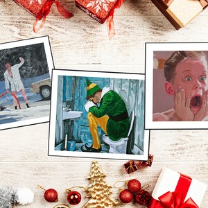 May include: Three rectangular art prints featuring movie scenes. The left print shows a person in a white robe outdoors in snow. The center print depicts a person in a green and yellow elf costume sitting on a toilet. The right print shows a close-up of a person with hands on their face in a shocked expression.
