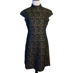 May include: A black and gold short-sleeved dress with a high neck and a floral pattern.
