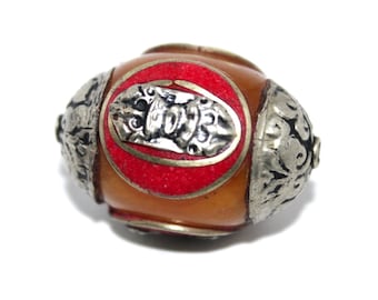 May include: A round amber bead with a silver and red design. The bead has a silver band around the center with a red enamel inlay and a silver design in the center. The bead is surrounded by silver floral designs.
