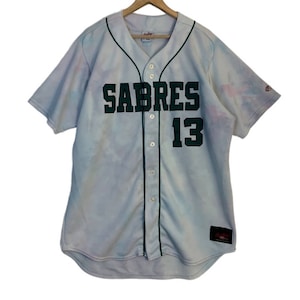 May include: A white tie-dye baseball jersey with green "SABRES" lettering and the number "13" on the front.