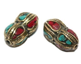May include: Two brass beads with red and turquoise inlay. The beads are oval shaped and have a decorative design.