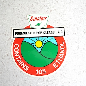 May include: Red and white sticker with a green dinosaur and the text "Sinclair" and "FORMULATED FOR CLEANER AIR". The sticker also has a green and blue illustration of hills and a sun with the text "CONTAINS 10% ETHANOL".