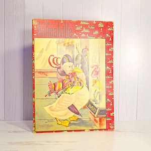 May include: Vintage "Animalville" box featuring an illustration of a duck wearing a hat, scarf, and glasses. The box has a red border with a repeating pattern of small houses. The duck is holding an umbrella and walking past a "HATS" sign.