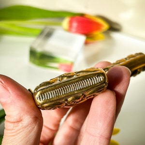 K&ouml;nnte beinhalten: Ein goldfarbener Flaschenverschluss aus Metall mit einem komplizierten Design. Der Verschluss weist ein detailliertes Muster aus Linien und Kurven auf, das ein dekoratives und elegantes Aussehen erzeugt.