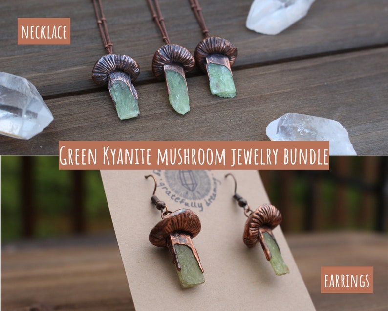 May include: A set of green kyanite mushroom jewelry, including a necklace and earrings. The necklace features three copper mushroom pendants with green kyanite stones. The earrings are copper mushroom dangles with green kyanite stones. The jewelry is displayed on a wooden surface with clear quartz crystals.