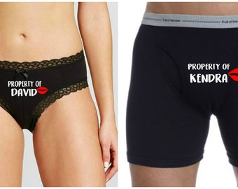 May include: A pair of black underwear with lace trim and the text "PROPERTY OF DAVID" with a red lip print. A pair of black boxer shorts with the text "PROPERTY OF KENDRA" with a red lip print.