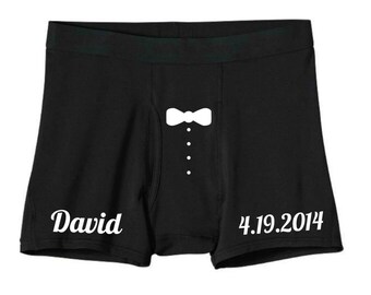 May include: Black boxer shorts with a white bow tie and tuxedo buttons design. The text "David 4.19.2014" is printed on the shorts.