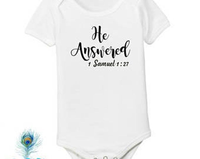 Pode incluir: Macac&atilde;o branco para beb&ecirc; com texto preto que diz "Ele respondeu" e "1 Samuel 1:27".