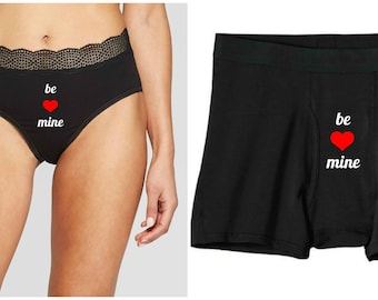 May include: Black underwear with a red heart and the text "be mine" printed on the front.