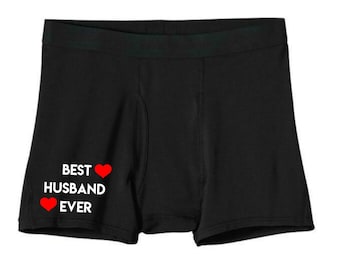 May include: Black boxer briefs with the text "BEST HUSBAND EVER" in white, accompanied by two red heart symbols. The underwear has a black elastic waistband.