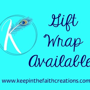 K&ouml;nnte beinhalten: T&uuml;rkisfarbener Hintergrund mit den Worten "Gift Wrap Available" in dunkelblauer Schrift. Ein Logo mit einem wei&szlig;en "K" und einer Pfauenfeder befindet sich in der oberen linken Ecke. Die Website-Adresse steht unten.
