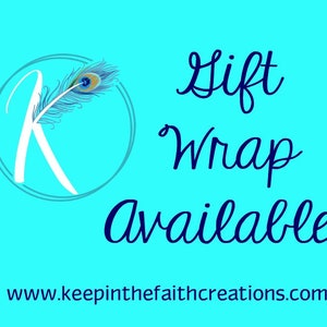May include: A turquoise blue background with a white letter "K" in a circle with a peacock feather. The text "Gift Wrap Available" is written in navy blue cursive. The website address "www.keepinthefaithcreations.com" is written in black at the bottom of the image.