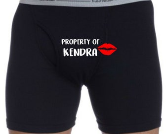 May include: Black boxer briefs with the text "PROPERTY OF KENDRA" and a red lipstick kiss mark.