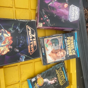 May include: A collection of vintage board games, including "Star Wars: X-Wing", "Star Wars: TIE Fighter", "Wheel of Fortune Deluxe Edition", and "Star Wars: Yoda Stories". The boxes feature colorful graphics and text.