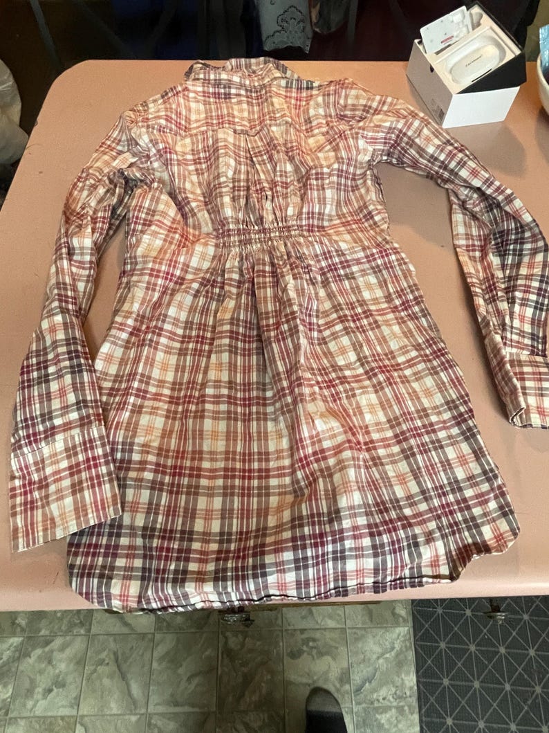 Op de afbeelding: Een geruit shirt met lange mouwen in tinten rood, bruin en cr&egrave;me. Het shirt heeft een geplooide taille en manchetten met knopen. De stof heeft een klassiek ruitpatroon.