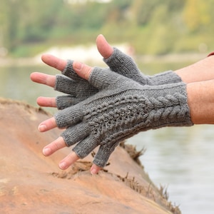 May include: A pair of gray fingerless gloves with a cable knit pattern. The gloves are made of a soft, warm material and are perfect for keeping your hands warm in the winter.