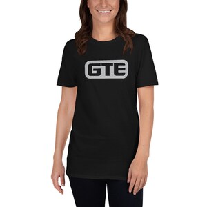 May include: Black short-sleeved t-shirt with a silver rectangle featuring the text "GTE" in black.