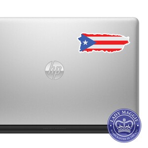 May include: A silver laptop computer with a sticker of the Puerto Rican flag on the back. The laptop has the HP logo on the lid and the text "HEWLETT-PACKARD" on the bottom. A blue and white sticker with the text "LADY MAGGIE HANDCRAFTED IN THE USA" and a crown is on the bottom right corner.