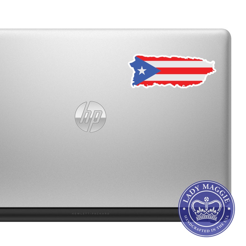 May include: A silver laptop computer with a sticker of the Puerto Rican flag on the back. The laptop has the HP logo on the lid and the text "HEWLETT-PACKARD" on the bottom. A blue and white sticker with the text "LADY MAGGIE HANDCRAFTED IN THE USA" and a crown is on the bottom right corner.