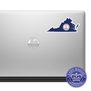 May include: A navy blue sticker in the shape of the state of Virginia, with the state seal in the center, is affixed to a silver laptop. A circular sticker with the text "LADY MAGGIE HANDCRAFTED IN THE USA" is in the lower right corner.