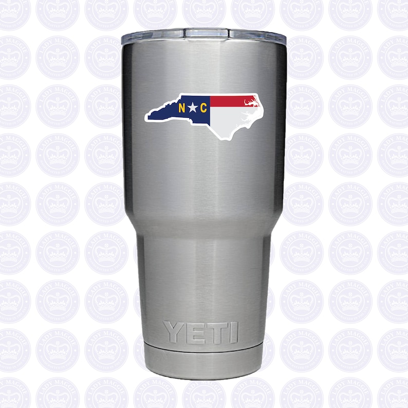 May include: A stainless steel Yeti tumbler with a North Carolina state outline sticker featuring the state flag colors and the letters "N*C".