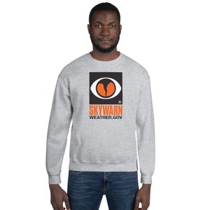 May include: A gray sweatshirt with a black and orange Skywarn logo. The logo features a stylized eye with a lightning bolt inside. The text "SKYWARN" and "WEATHER.GOV" are printed below the logo.