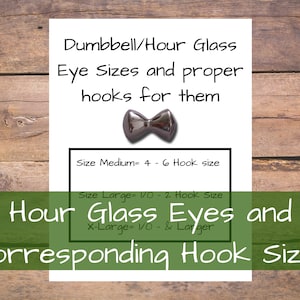 May include: A white card with black text that reads "Dumbbell/Hour Glass Eye Sizes and proper hooks for them".  The card also includes a chart with the text "Size Medium= 4 - 6 Hook size", "Size Large= 1/0 - 2 Hook Size", and "X-Large= 1/0 - & Larger".  The card is on a wooden background.