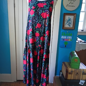 Könnte beinhalten: Ärmelloses, bodenlanges Kleid auf einer Schaufensterpuppe. Das Kleid hat einen dunkelblauen Hintergrund mit einem roten Blumenmuster und Paisley-Akzenten. Das Kleid hat einen Stufenrock und einen Rundhalsausschnitt.