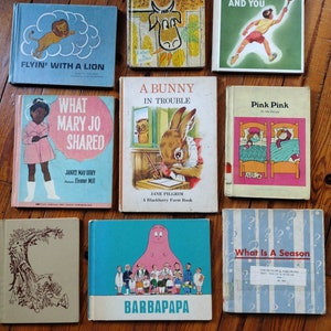 Puede incluir: Una colección de diez libros infantiles vintage con portadas coloridas. Los libros incluyen títulos como "La Vaca Curiosa", "Lo Que Mary Jo Compartió", "Un Conejo En Problemas", y "Rosa Rosa".