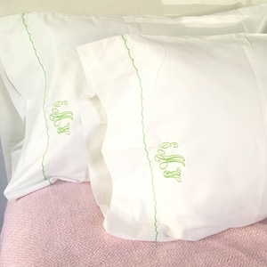 May include: Two white pillowcases with green embroidered trim and the monogram "B.J.S." in green thread.