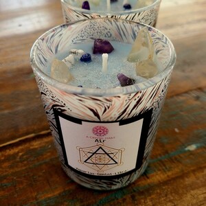 May include: A blue candle with crystals and a label that reads "A Crystal Habit Air Aquarius-Gemini-Libra".