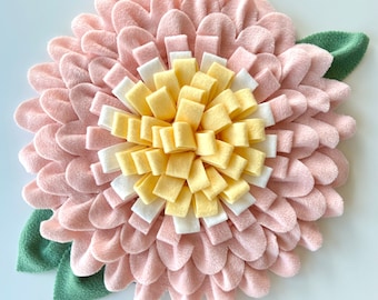 May include: A pink felt flower with a yellow and white felt center. The flower has a green felt leaf on each side.
