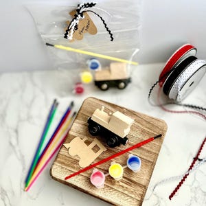 May include: A wooden train craft kit with a wooden train, paint, brushes, and ribbon. The kit includes a wooden train, paint, brushes, and ribbon. The kit is packaged in a clear bag with a tag that says "From Mason".