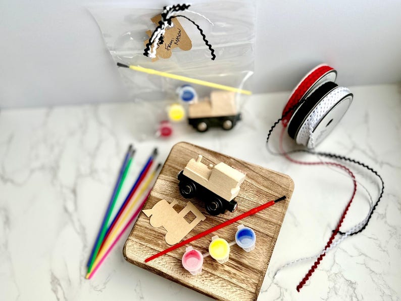 May include: A wooden train craft kit with a wooden train, paint, brushes, and ribbon. The kit includes a wooden train, paint, brushes, and ribbon. The kit is packaged in a clear bag with a tag that says "From Mason".