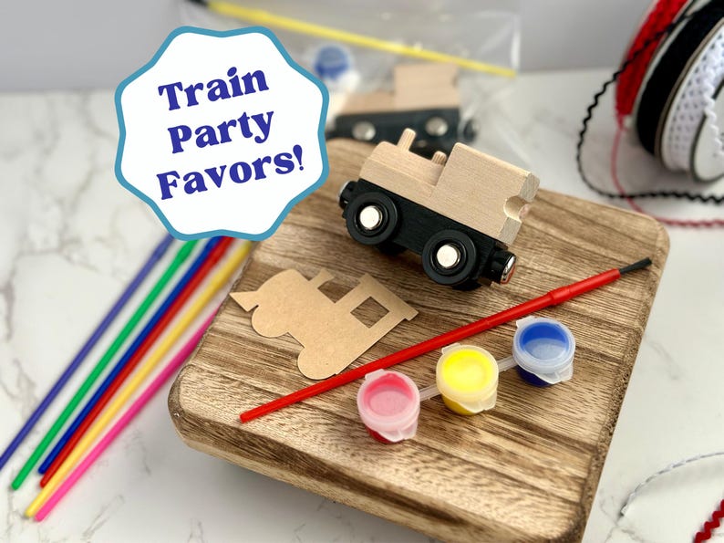 May include: Wooden train party favors set with paint, brushes, and colorful straws. The set includes a wooden train, a train cutout, and small paint pots in pink, yellow, and blue. The image also includes the text "Train Party Favors!"