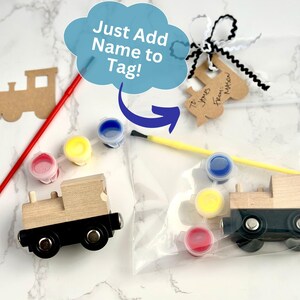 May include: Wooden train craft kit with paint and brushes. The kit includes a wooden train, paint pots in red, yellow, and blue, and a tag that says "Just Add Name to Tag!"
