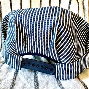 May include: A blue and white striped baseball cap with a black adjustable strap. The cap is made of a soft, comfortable fabric.