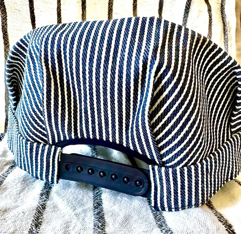 May include: A blue and white striped baseball cap with a black adjustable strap. The cap is made of a soft, comfortable fabric.