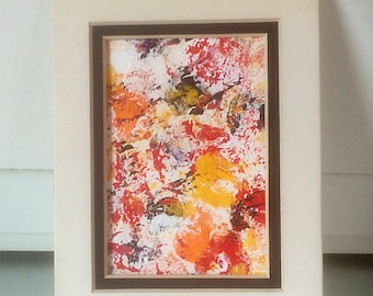 May include: Abstract painting in a white frame with a brown mount. The painting features a colourful abstract design with shades of red, orange, yellow, white, and green.