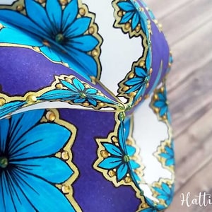 May include: A close-up of a folded paper ornament with a blue and gold floral pattern. The ornament is made of paper and has a 3D effect.
