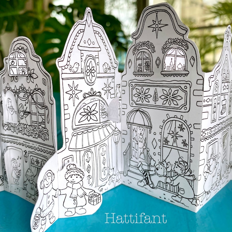 May include: A black and white printable papercraft of a Christmas village with three houses, each with a unique design. The houses have windows, doors, and decorative details. There are two people standing in front of the houses, and a cat is walking by.