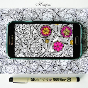May include: A black Samsung smartphone with a green screen displaying a colorful mandala design. The phone is lying on a white surface with a black and white patterned background. A Micron 02 archival ink pen is also visible.