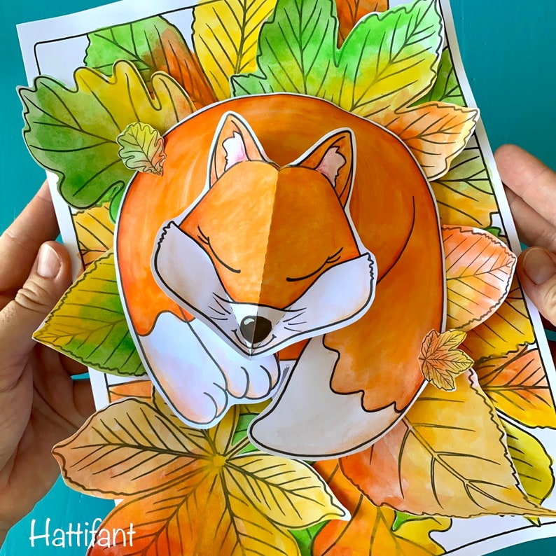 May include: A printable craft activity featuring a fox curled up in a bed of colorful autumn leaves. The fox is orange with white accents and closed eyes. The leaves are shades of yellow, orange, and green.