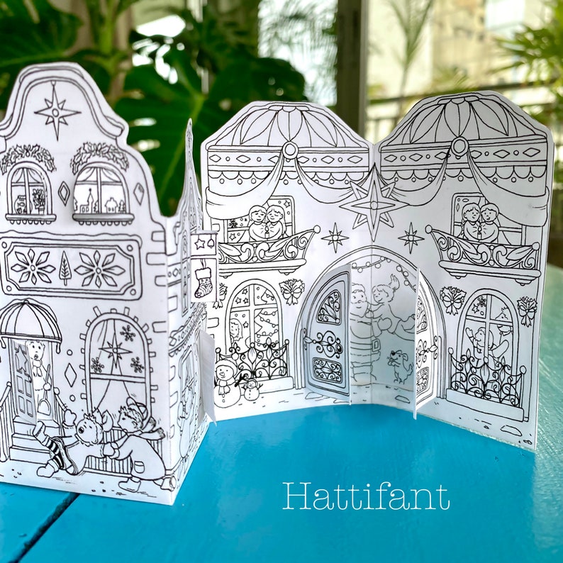 May include: A black and white printable papercraft of a gingerbread house with a star on top. The house has windows, a door, and a balcony. The text "Hattifiant" is printed below the house.
