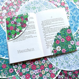 May include: An open book with a floral patterned bookmark. The book is titled "Hattifant" and the text on the page is in German. The book is surrounded by colorful floral patterned circles.