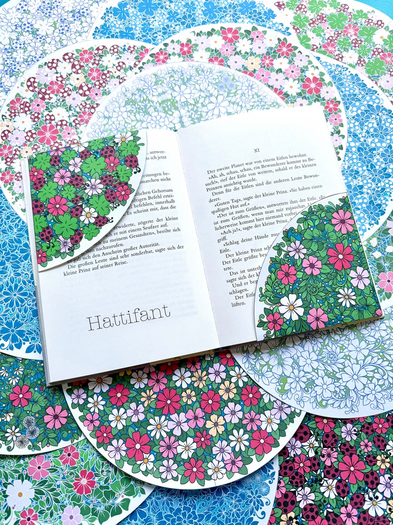 May include: An open book with a floral patterned bookmark. The book is titled "Hattifant" and the text on the page is in German. The book is surrounded by colorful floral patterned circles.