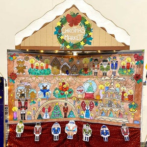 May include: A hand-painted backdrop depicting a Christmas market scene with a gingerbread house, nutcrackers, and a snow globe. The backdrop is decorated with lights and a wreath that says "Christmas Market". The bottom of the backdrop has the word "Hattifant" written in cursive.